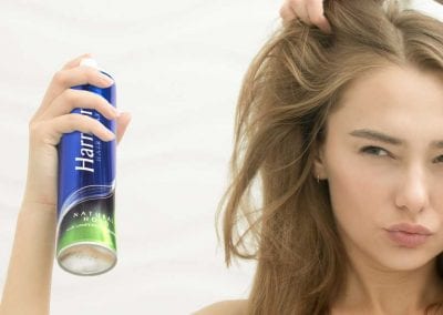 Teen Girl Lifting Segments of Hair and Spraying Harmony Hairspray